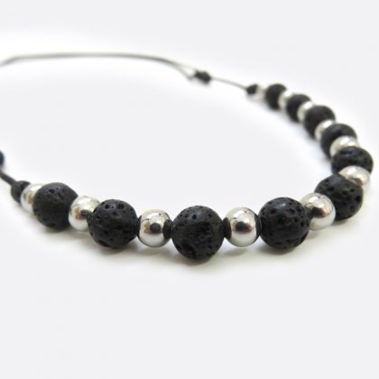 Collana realizzata a mano con perle di pietra lavica da 6 mm, distanziate da perle in acciaio inox da 4 mm. La lunghezza della collana è regolabile attraverso nodini scorrevoli.