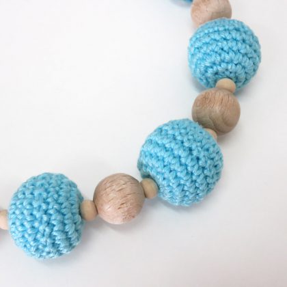 Collana realizzata a mano, composta da perle di legno naturale e da morbide palline fatte all'uncinetto, imbottite di soffice fibra di viscosa.