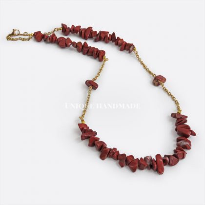 Collana realizzata a mano con sassolini di diaspro rosso montati su una catenella di acciaio dorato.